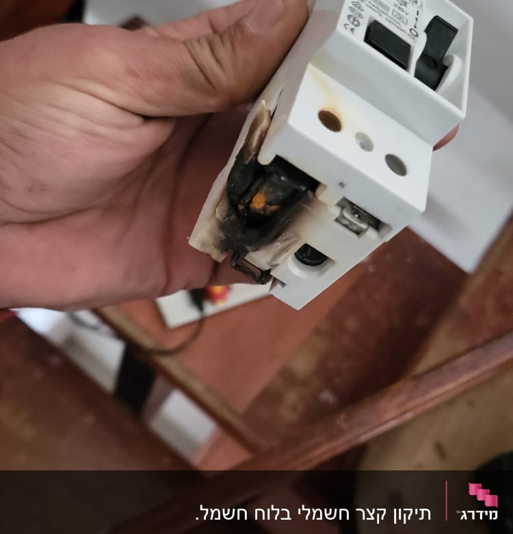 יד מחזיקה מפסק חשמלי שרוף עם סימני נזק